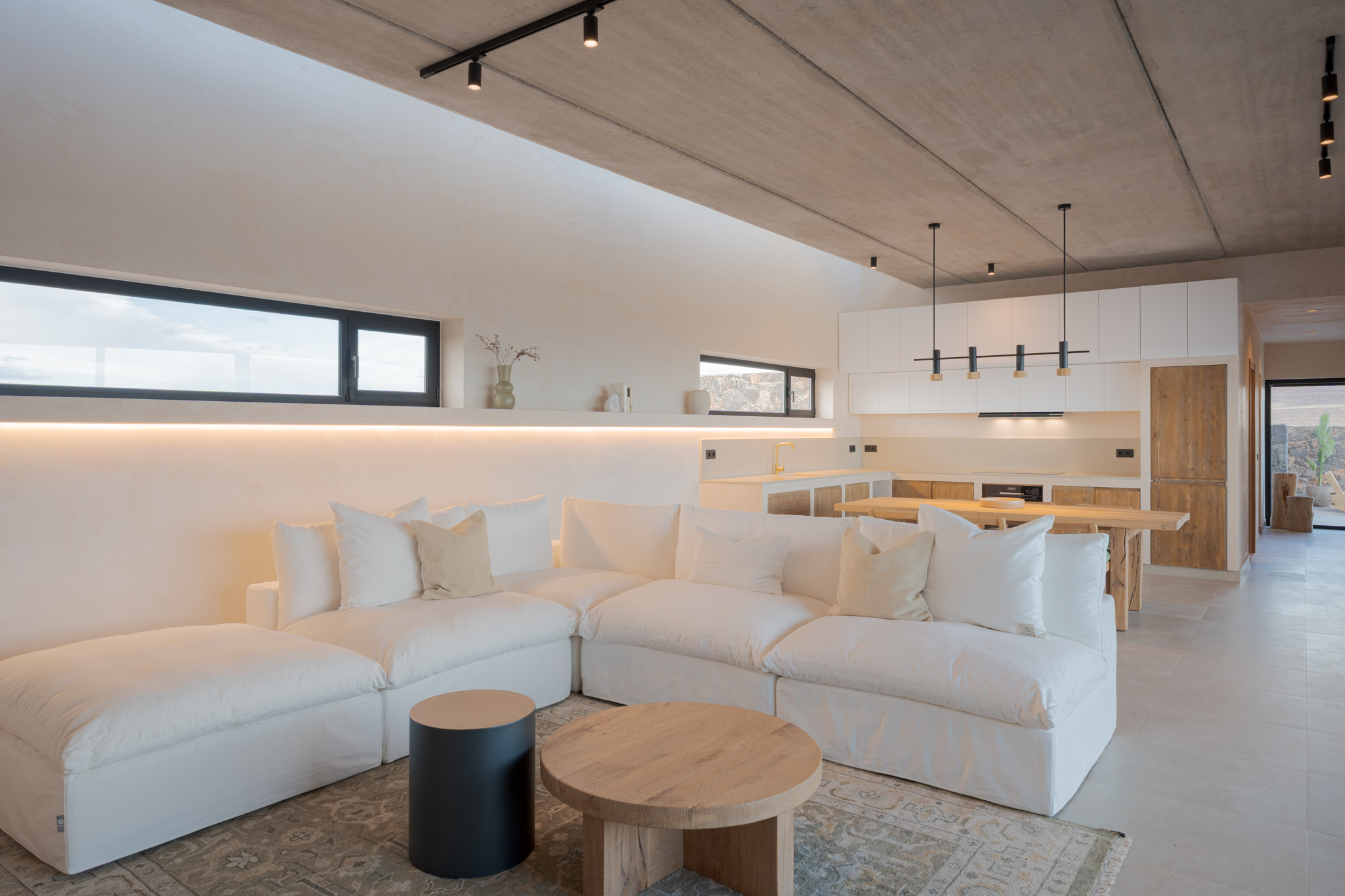 Open-plan living room with white sofa, oak coffee table and modern kitchen